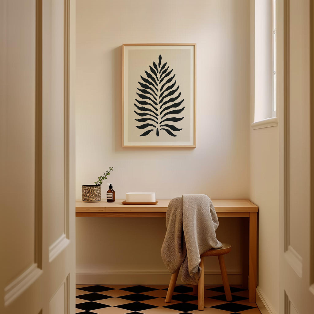 a cozy corner of a room with a wooden desk, a framed abstract leaf design, and a small plant on the desk. The room has a checkered floor and a window, creating a warm and inviting atmosphere.