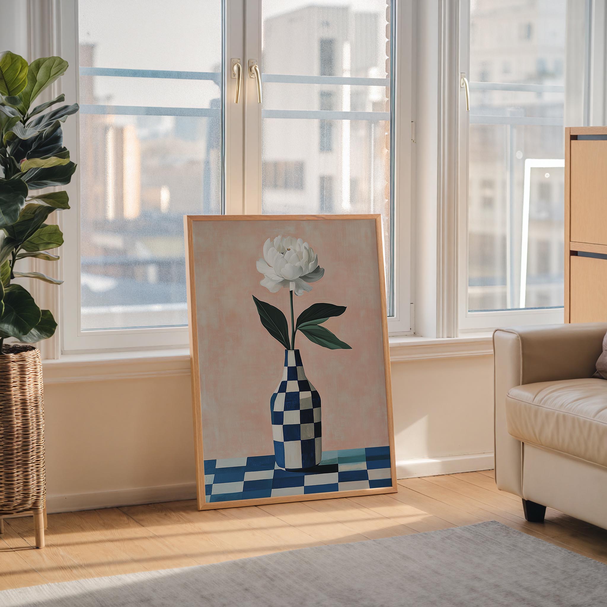a large painting of a white flower in a checkered vase, placed on a wooden floor in front of a window overlooking a cityscape.