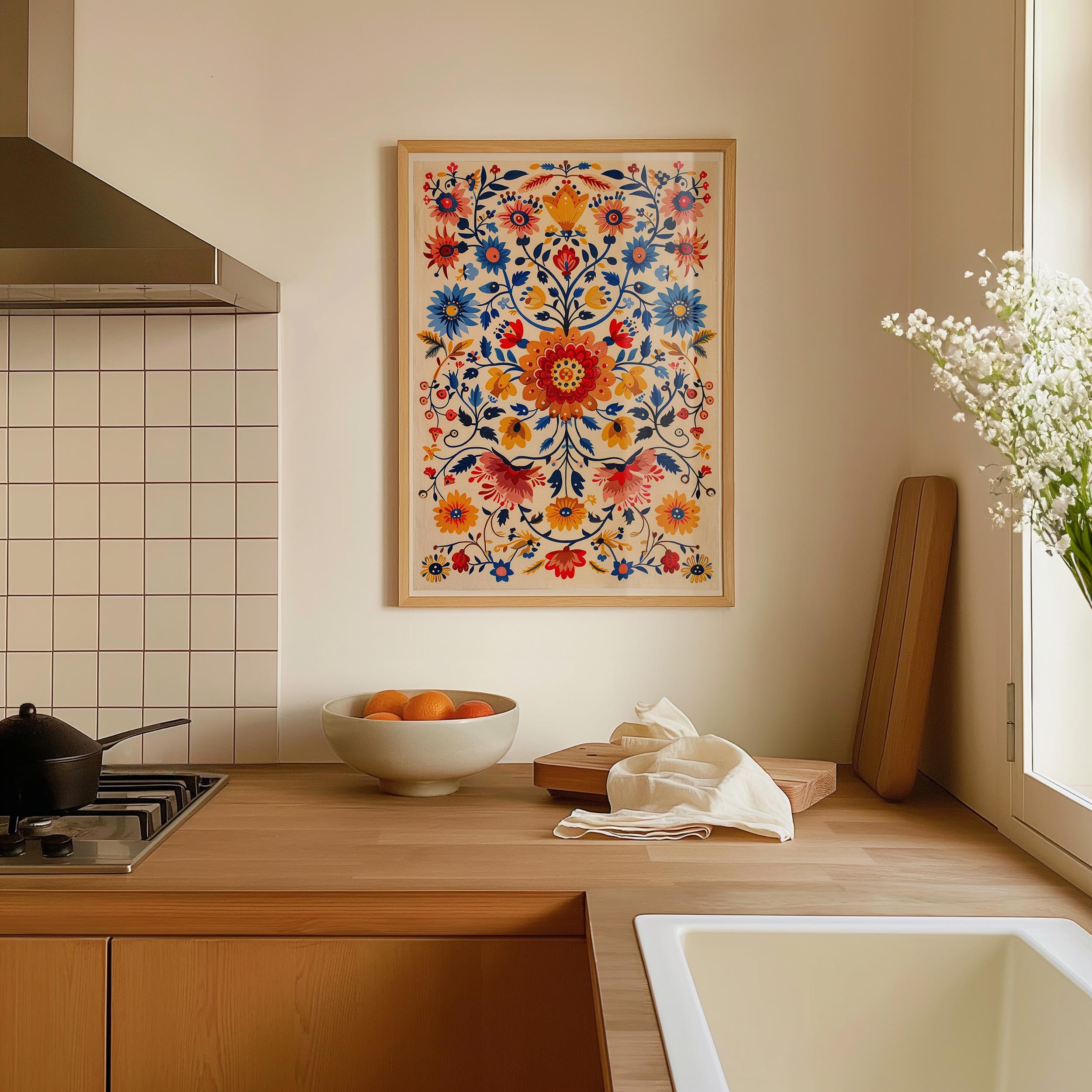 a kitchen counter with a bowl of fruit, a vase of flowers, and a framed floral print hanging on the wall above the counter.