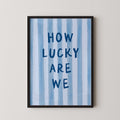 a framed poster with the text "HOW LUCKY ARE WE" written on it.