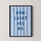 a framed poster with the text "HOW LUCKY ARE WE" written on it.
