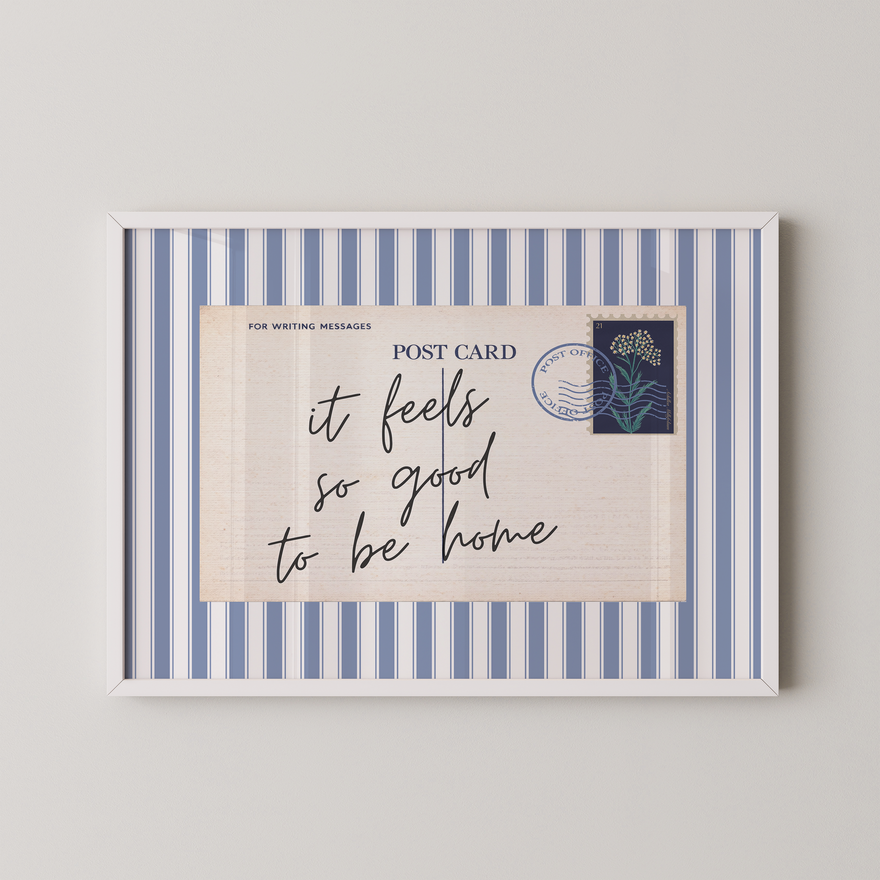 The image is a framed postcard with a blue and white striped border, featuring a handwritten message that reads "it feels so good to be home".