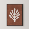 a framed print of a white leaf with a brown background.