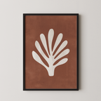 a framed print of a white leaf with a brown background.