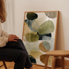 A person is sitting in a chair in front of a large abstract painting on the wall.