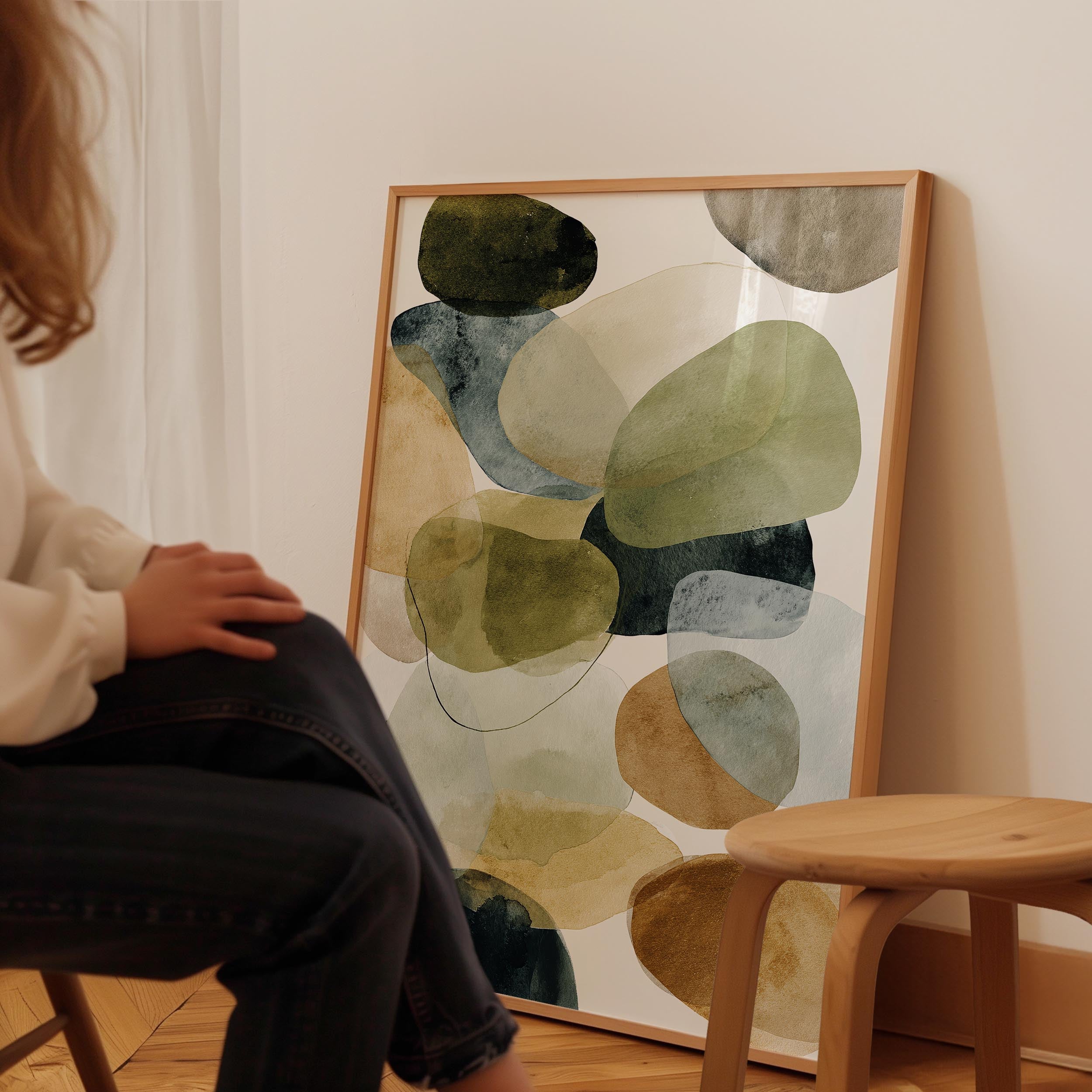 A person is sitting in a chair in front of a large abstract painting on the wall.