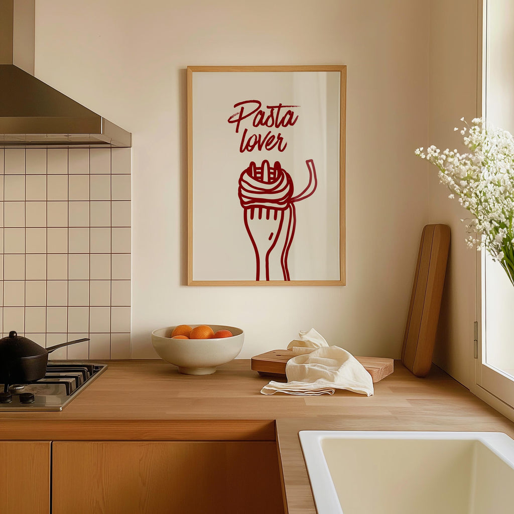 a kitchen counter with a framed poster of a red spaghetti noodle with a fork and a bowl of fruit, including oranges, on it.