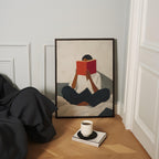 a person sitting on a bed, reading a book, with a cup of coffee and a book on a table in front of them.