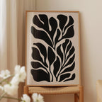 a framed artwork with a striking black and white abstract design of leaf-like shapes.