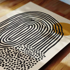 a close-up view of a piece of art with a striking abstract design. The artwork consists of a large, curved shape in black and white, with a smaller, circular shape in black and white with a polka dot pattern. The composition creates a visually interesting contrast between the two shapes.