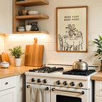 a cozy kitchen scene with a white stove, wooden cutting board, and various kitchen accessories such as bowls, cups, and a potted plant. Above the stove, there is a framed illustration of a dining table with chairs, and the phrase "GOOD FOOD GOOD MOOD" is written above it.