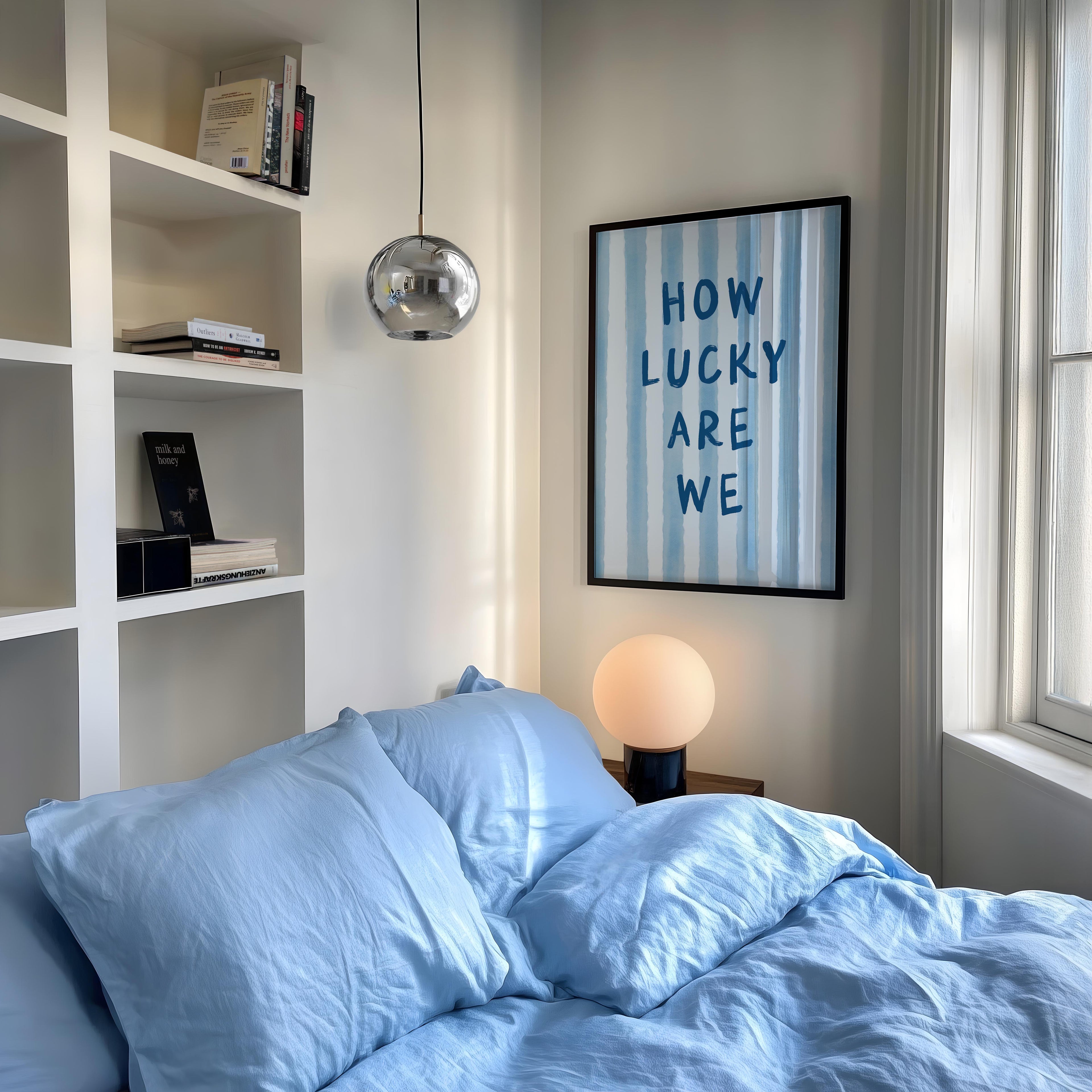 a cozy bedroom with a bed covered in blue sheets, a framed poster on the wall, and a bookshelf filled with books.