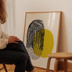 A person is sitting in a chair in front of a large abstract painting on the wall.