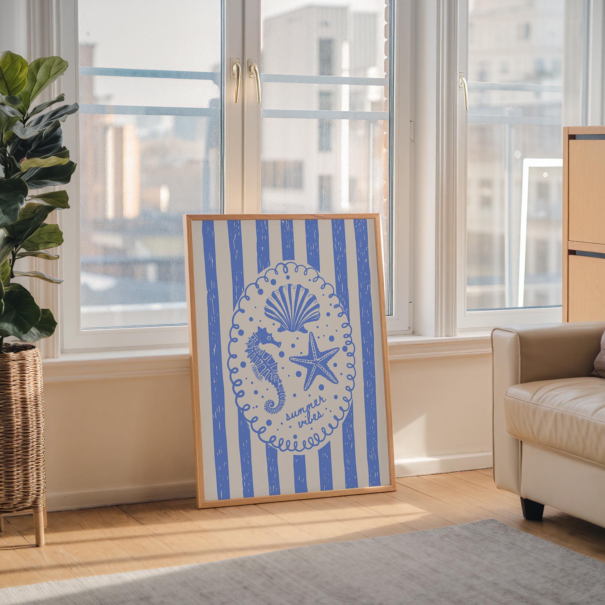 a framed artwork with a blue and white striped design, depicting a seahorse and starfish, placed on a wooden floor in front of a window.