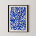 The image is a framed print featuring a repeating pattern of blue and white leaf-like shapes, creating a visually striking and intricate design.