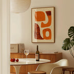 a dining area with a table, a bottle of wine, and a framed abstract artwork on the wall.