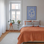 a cozy bedroom with a large bed, a window with a plant on the sill, and a framed artwork featuring a seahorse and starfish.