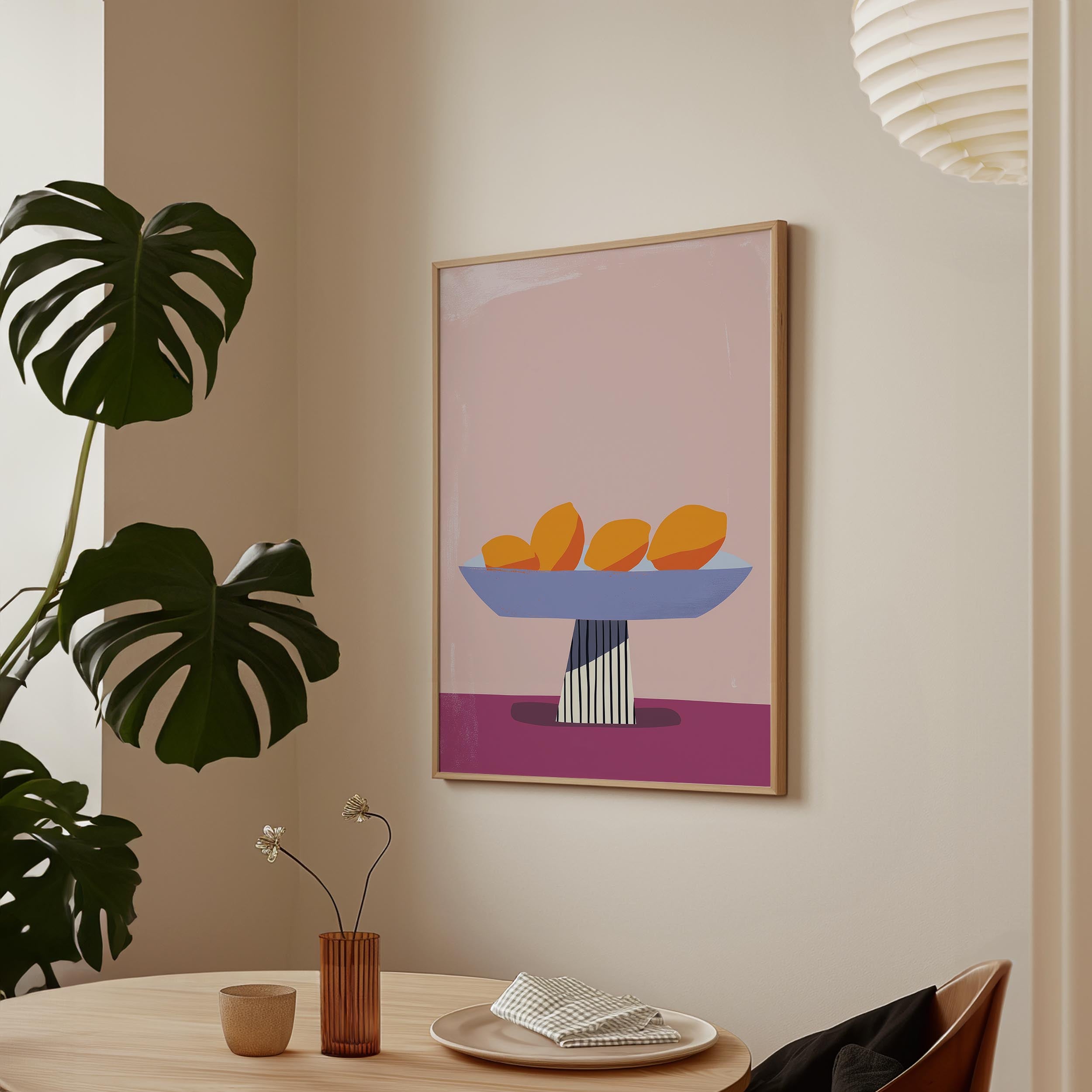 a minimalist dining area with a table, a vase of flowers, and a framed artwork depicting a bowl of fruit on a pink background.
