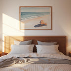 a serene bedroom scene with a wooden headboard and a framed painting of a beach scene above it.