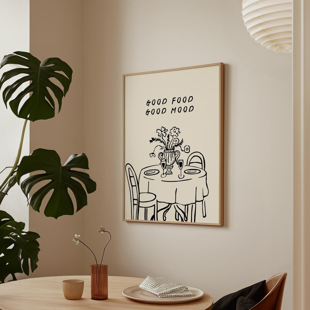 a framed poster with a simple illustration of a table set for a meal, accompanied by the text "GOOD FOOD GOOD MIND" above it.