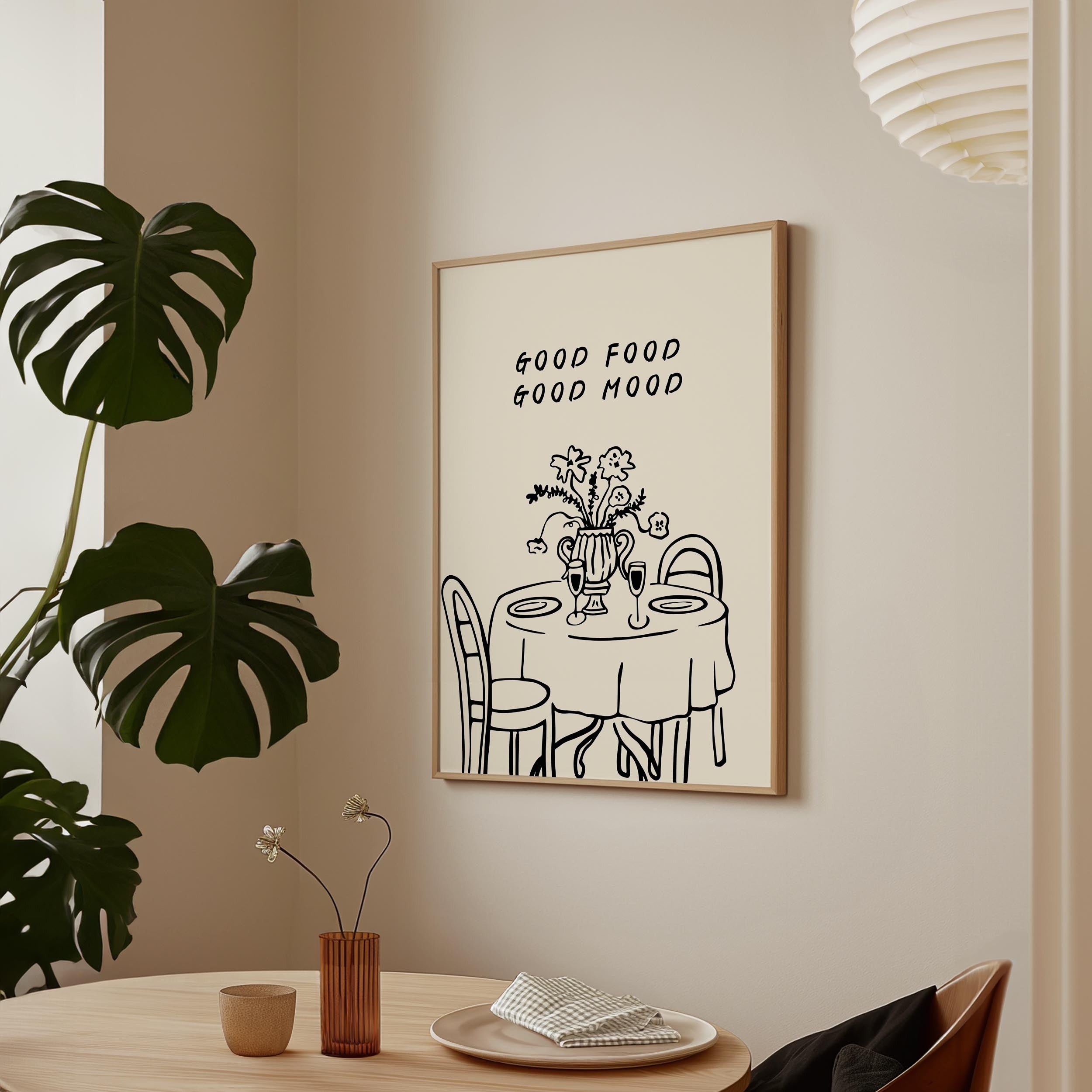 a framed poster with a simple illustration of a table set for a meal, accompanied by the text "GOOD FOOD GOOD MIND" above it.