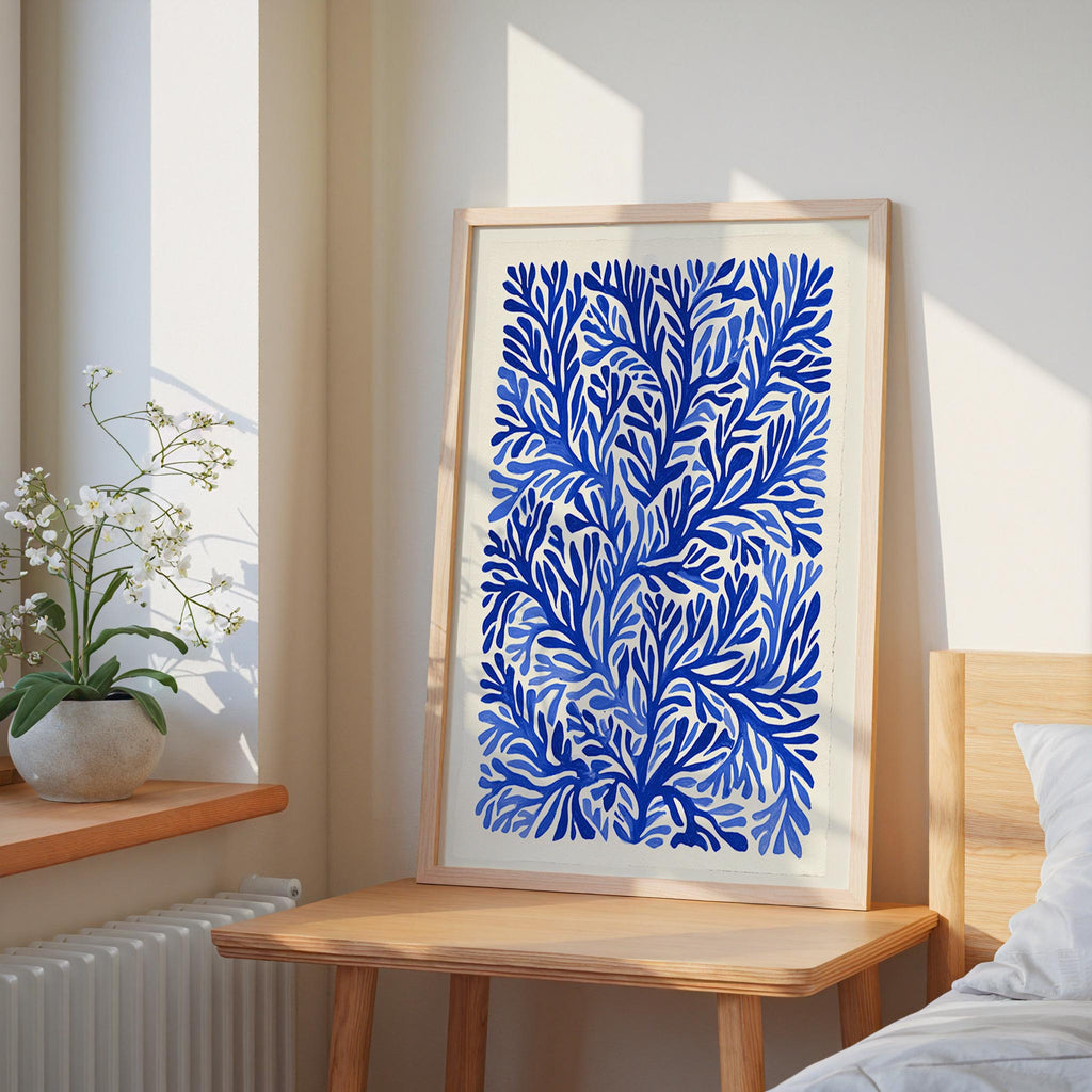 a large blue and white abstract painting hanging on a wall, placed on a wooden table next to a window.