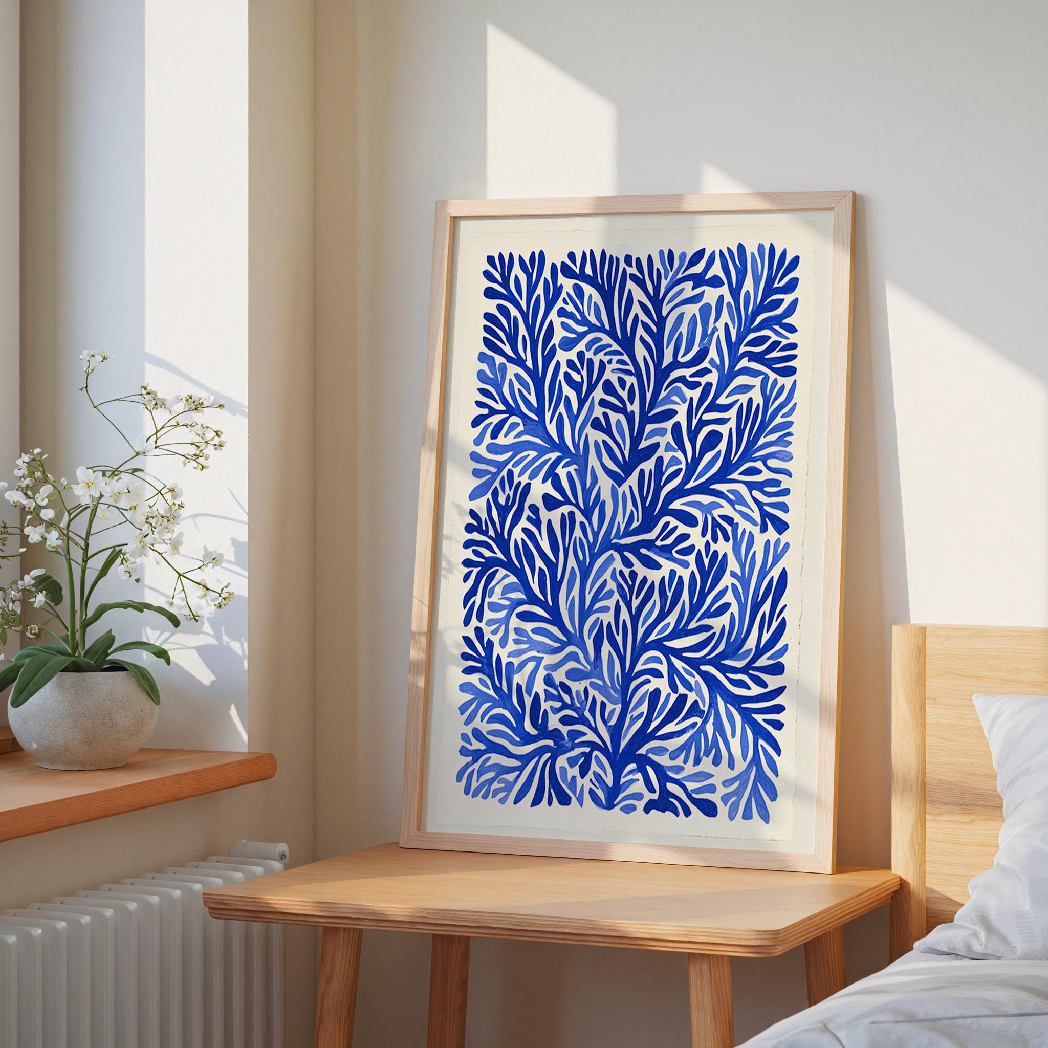 a large blue and white abstract painting hanging on a wall, placed on a wooden table next to a window.
