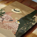 A woman in a striped dress and hat is sitting on a bench, holding a glass of wine and enjoying the outdoors.