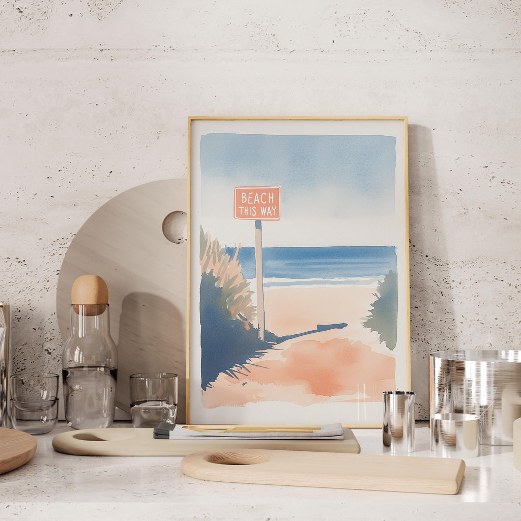 a framed painting of a beach scene with a sign that says "BEACH THIS WAY" in the foreground.