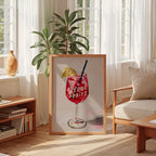a framed painting of a red drink with a straw, placed in a living room setting with a window, plants, and furniture.