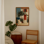 a cozy corner of a room with a painting of a house, a potted plant, and a wooden chair.
