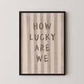 a framed print with the text "HOW LUCKY ARE WE" written on it.