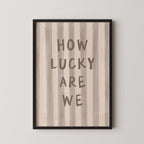 a framed print with the text "HOW LUCKY ARE WE" written on it.