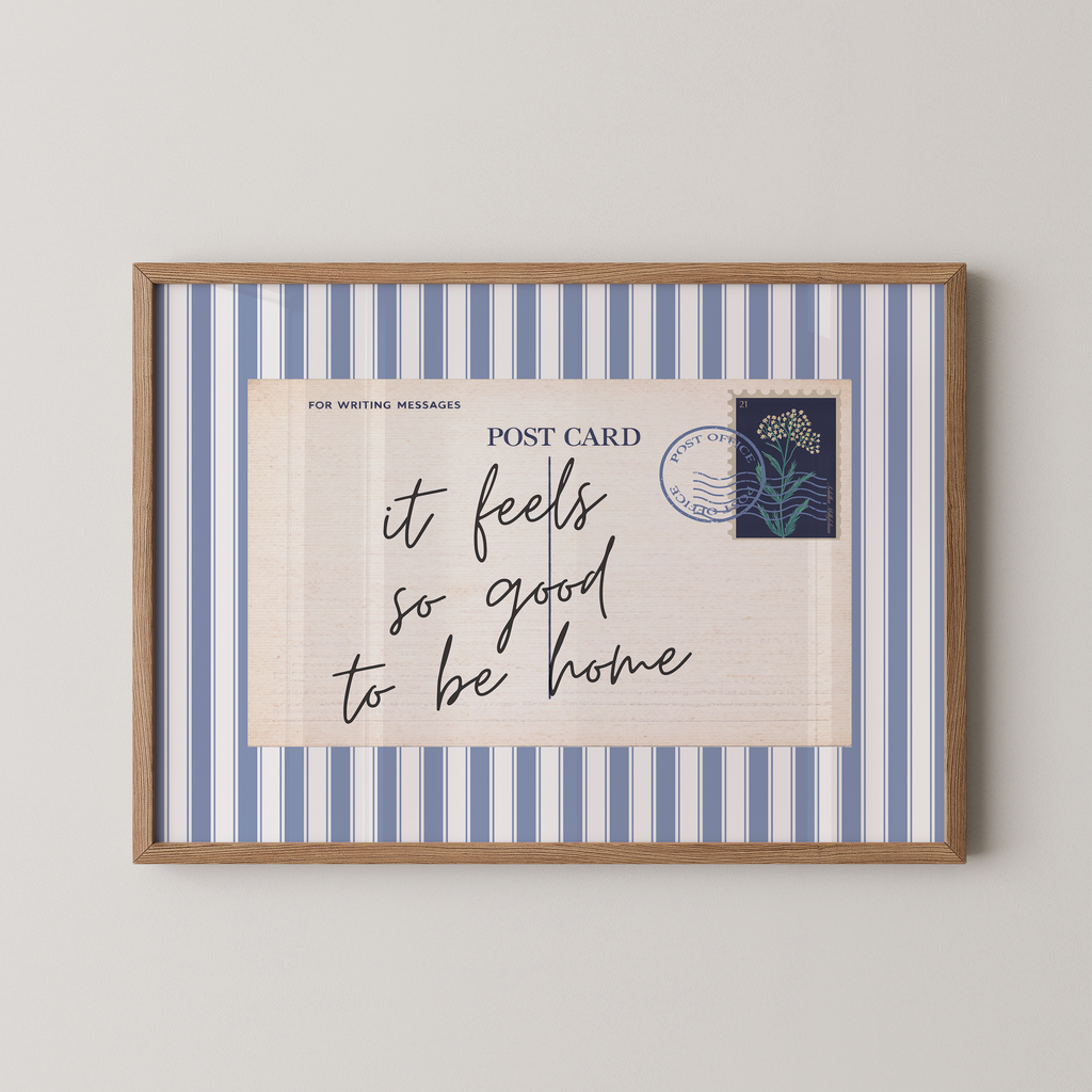 The image is a framed print with a blue and white striped border, featuring a handwritten message that reads "it feels so good to be home".