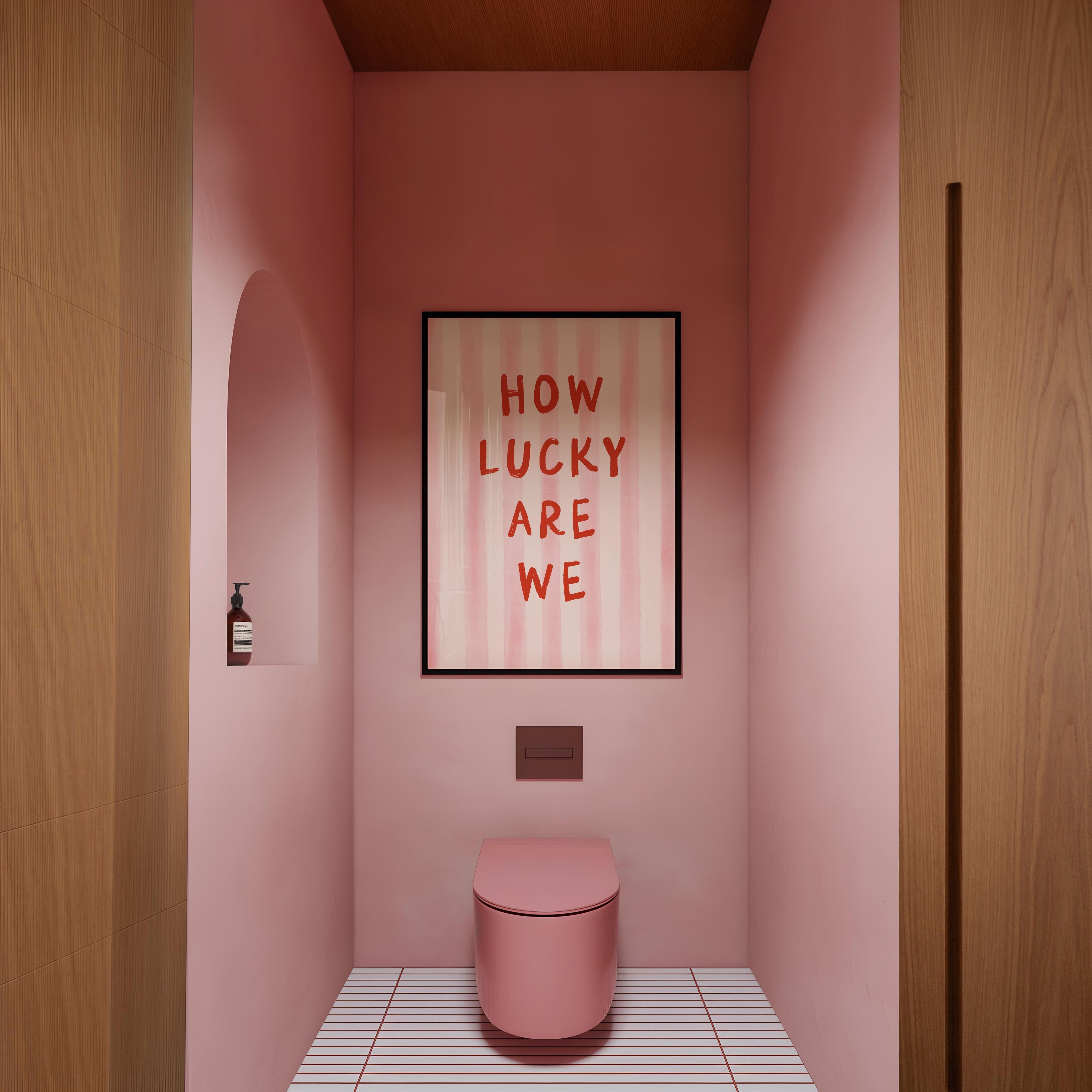a bathroom with a pink toilet and a framed text that reads "HOW LUCKY ARE WE".