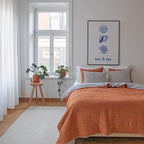 a cozy bedroom with a large bed, a window with a view of the outside, and a framed artwork featuring seashells and the words "sun & sea".
