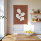 a kitchen counter with a bowl of lemons, a framed plant-like artwork, and shelves displaying various jars and containers.