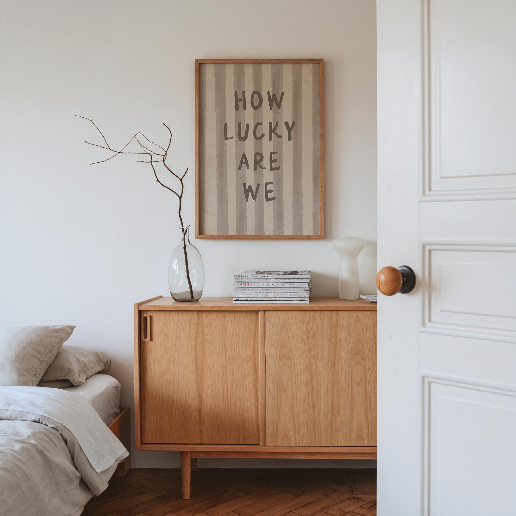 a bedroom with a wooden dresser, a framed quote, a vase with branches, and a stack of books.