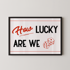 A framed poster with the text "How LUCKY ARE WE" and two dice graphics.