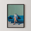 A woman is sitting on a blue couch, reading a book.
