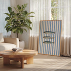 a cozy living room with a large potted plant, a wooden coffee table, and a framed artwork featuring three fish on a blue and white striped background.
