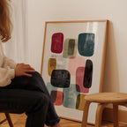 A person is sitting on a chair in front of a large abstract painting on the wall.