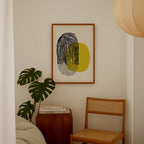 a cozy corner of a room with a wooden chair, a wooden side table, and a framed abstract art piece on the wall.