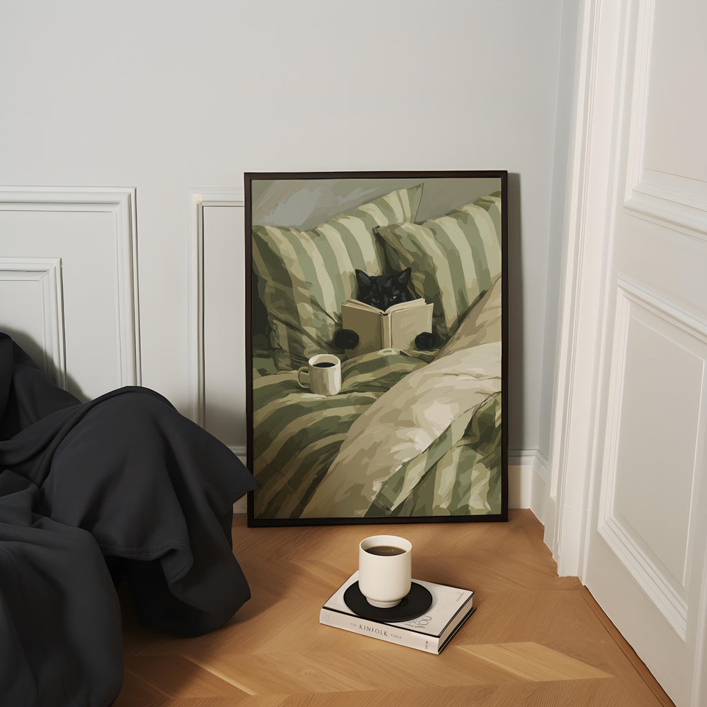 a cozy scene with a framed painting of a cat sitting on a bed, holding a book, and a cup of coffee on a wooden floor.