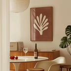 a dining room with a table set for two, a bottle of wine, and a framed artwork on the wall.