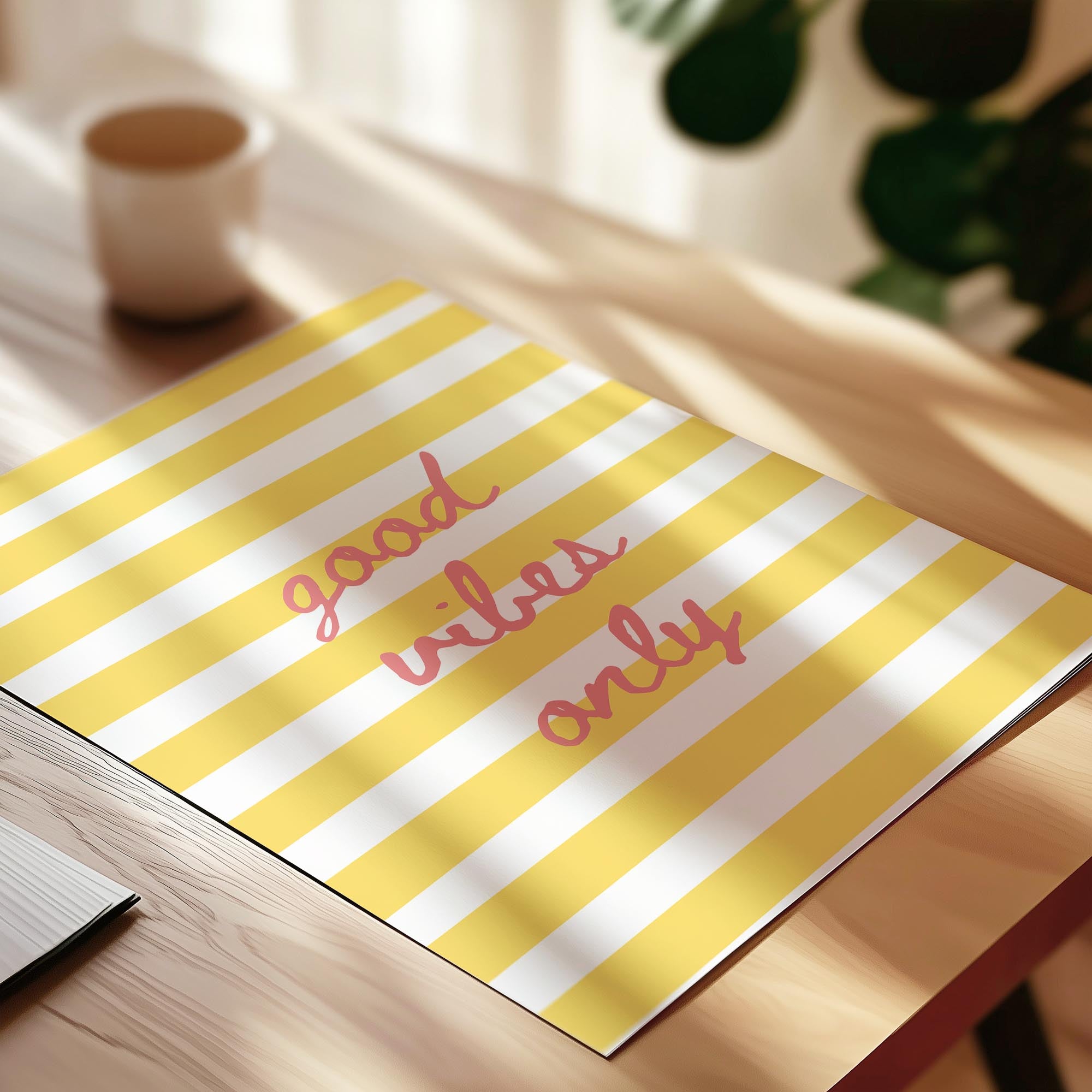 A yellow and white striped notebook with the text "good vibes only" written on it, placed on a wooden surface.