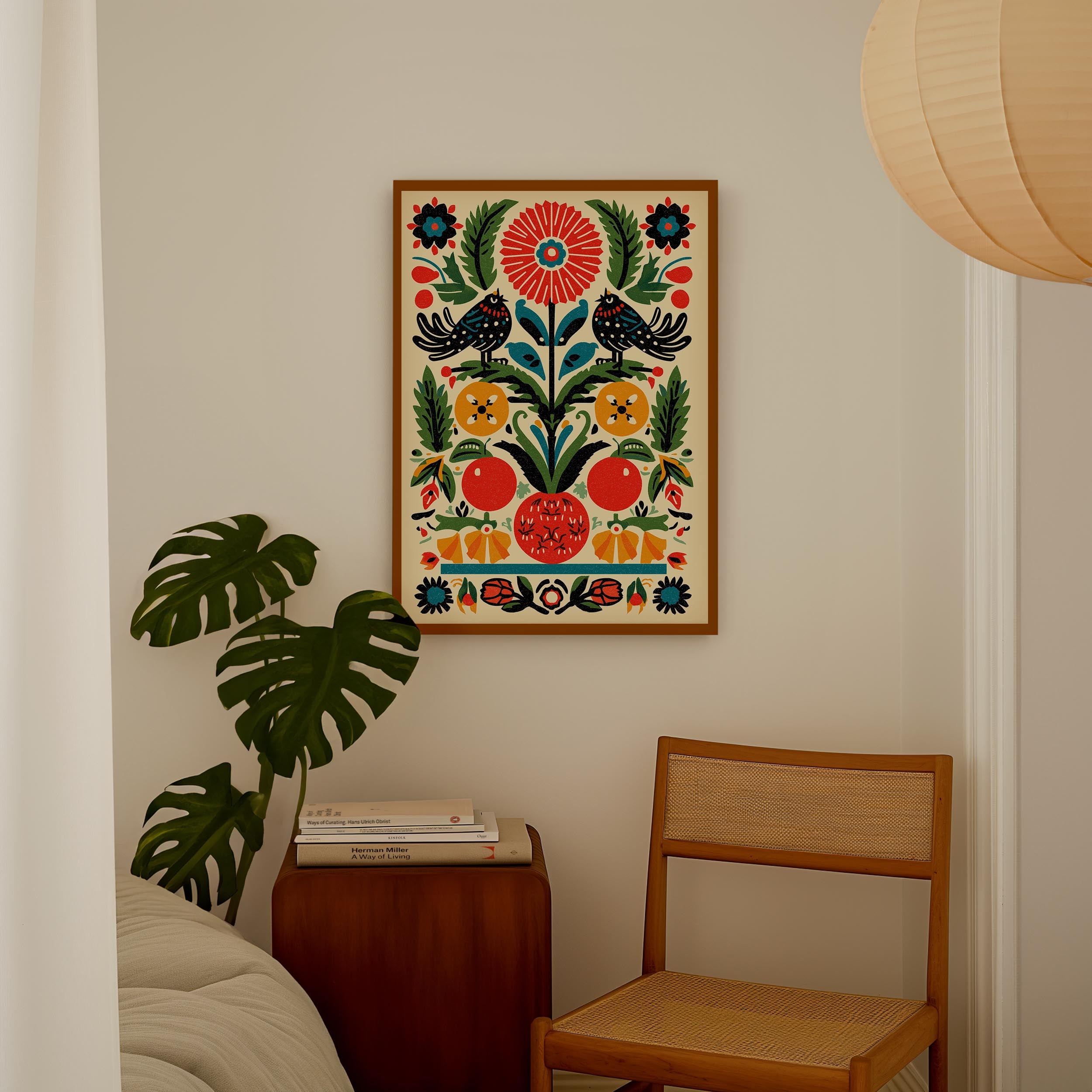 a cozy corner of a room with a wooden chair, a small table with books, and a large, colorful floral print hanging on the wall.