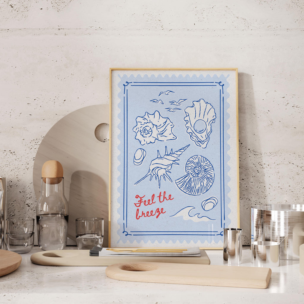 a framed artwork with illustrations of seashells and a bottle of wine, placed on a kitchen counter.