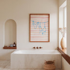 a bathroom with a white bathtub, a framed artwork of a woman's silhouette hanging on the wall, and a window with a vase of flowers.