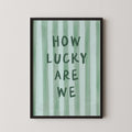 a framed poster with the text "HOW LUCKY ARE WE" written on it.